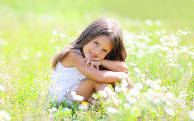 Naklejka na ściany i meble Little girl child sitting on the grass in sunny spring meadow
