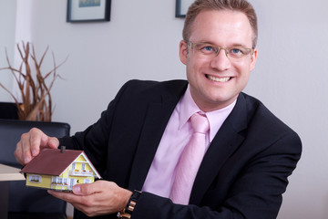 Gesch&auml;ftsmann zeigt Miniaturhaus Portr&auml;t