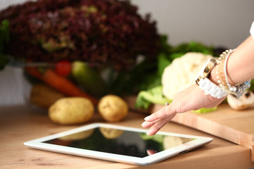 Young woman using a tablet computer to cook in her kitchen