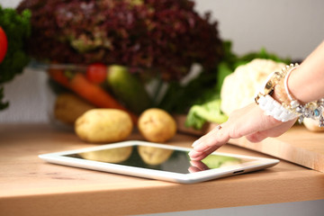 Young woman using a tablet computer to cook in her kitchen