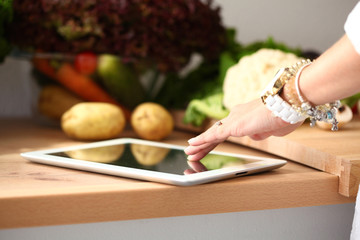 Young woman using a tablet computer to cook in her kitchen