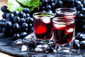 Cold dark grape juice with ice, selective focus