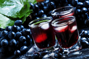 Cold dark grape juice with ice, selective focus