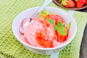 Ice cream strawberry with syrup and spoon in bowl on board