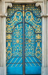 Blue door decorated with golden adornment with iron handle and stone portal