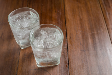 Glasses with ice cubes on wooden background