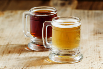 Light and dark beer in old-fashioned circles on old wooden table