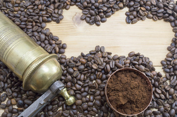 Coffee beans, grinder and on a wooden table with grounded coffe