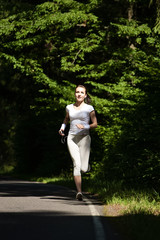 Beautiful running girl. Female runner jogging during outdoor workout on trail in park or forest. Caucasian woman run with heart rate monitor gadget athlete outside.