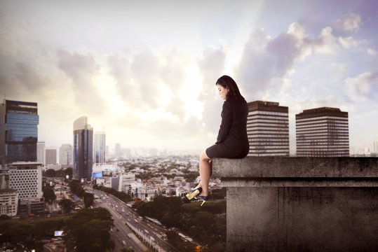 Business woman sitting on building rooftop