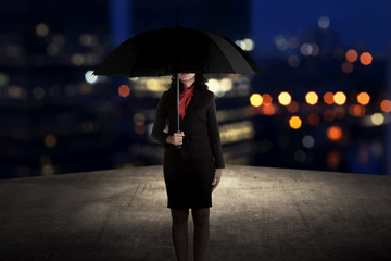 Business woman holding umbrella standing on the rooftop