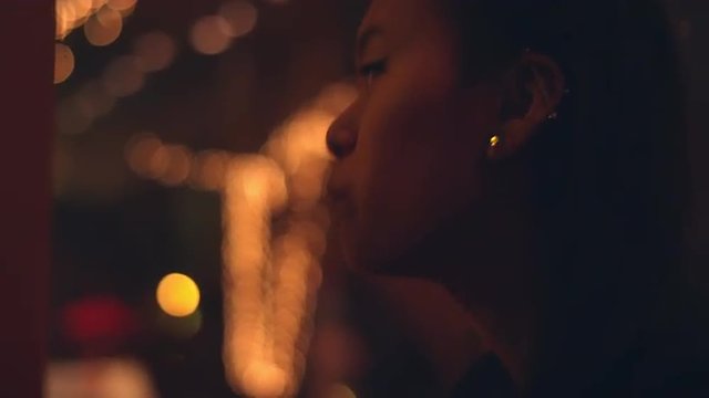 A young woman talking on a romantic dinner date with city lights behind her