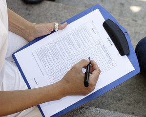 Close-up of a woman's hand filling out a survey.