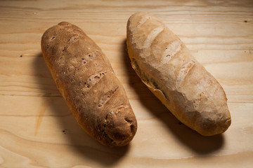 Due pagnotte di pane fatte a mano su un tavolo di legno . 