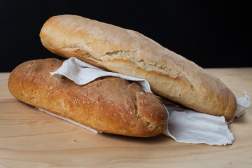 Due pagnotte di pane ai sei cereali  su un tavolo di legno. Sfondo nero