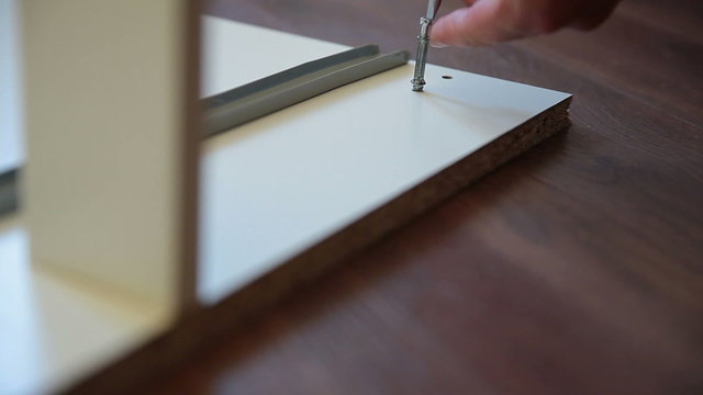 Man screws fastening the screw into the wall of the chest.