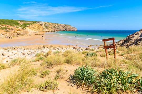 View of beautiful Zavial beach with surfers on ocean water, Portugal