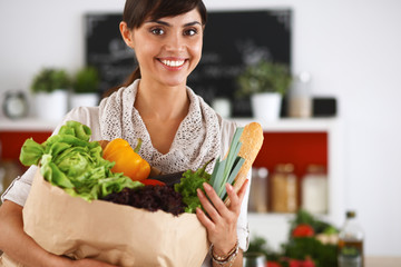 Young woman holding grocery shopping bag with vegetables