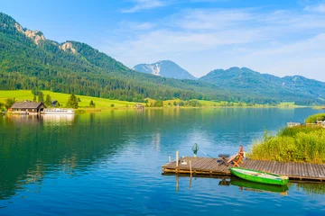 Foto op Plexiglas Unidentified man sitting on wooden pier and fishing on shore of Weissensee lake in summer landscape of Alps Mountains, Austria © pkazmierczak