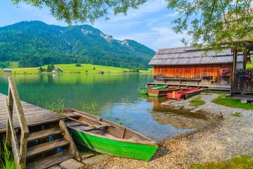 Zelfklevend Fotobehang Vissersboten en houten huizen aan de oever van het Weissensee-meer in het zomerlandschap van het land van Karinthië, Oostenrijk © pkazmierczak