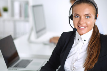 Happy female wearing headset and sitting on the desk