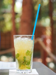 Fresh ice tea made of green tea, mint and lime served in a big glass with long blue straw.