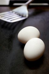 stainless steel spatula and eggs on metal pan