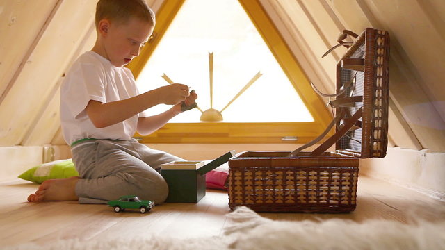 Boy's discovering the contents of the chest with toys in the attic 