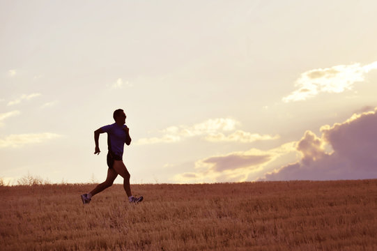 Profile Silhouette Of Young Man Running In Countryside Training In Summer Sunset