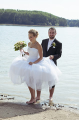 Groom and bride going barefoot at a lake
