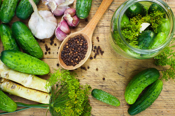 Preparations to make homemade pickles with cucumbers, garlic, dill and horseradish on wooden board