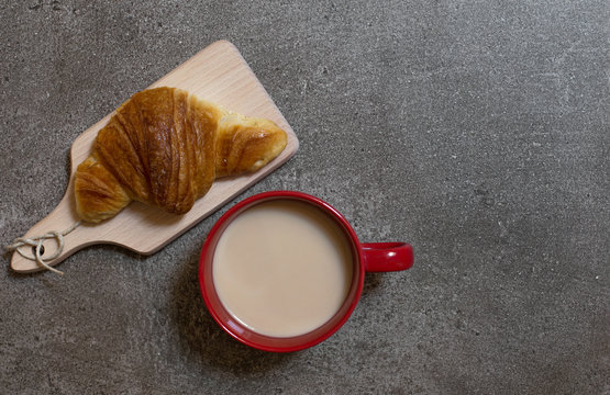 Coffee with milk on cutting baord with croissant