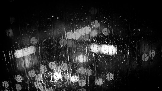 City lights as seen through the window glass during the rain