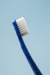 Blue toothbrush covered with water drops