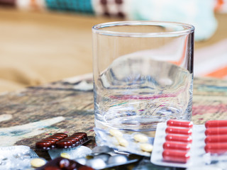 empty glass and pile of pills close up on table