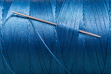 sewing needle in blue thread bobbin