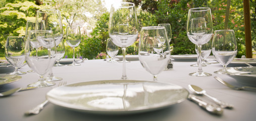 Glasses, plates, silverware on a table for a party.