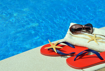 Pair of red flip-flops, sunglasses, towel, starfish