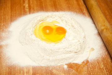raw eggs in the flour on a wooden table