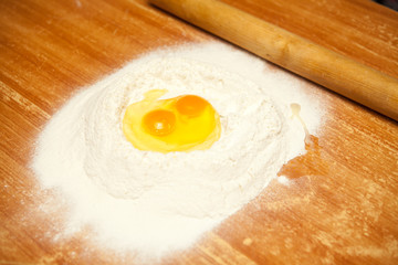 raw eggs in the flour on a wooden table