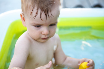 Fototapeta na wymiar child bathes in inflatable pool outdoors, close-up portrait