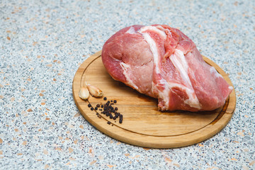 large piece of raw meat with pepper and garlic on a cutting boar