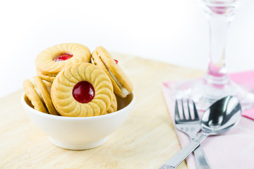 Sandwich cookies with cream and strawberry flavoured jam on whit