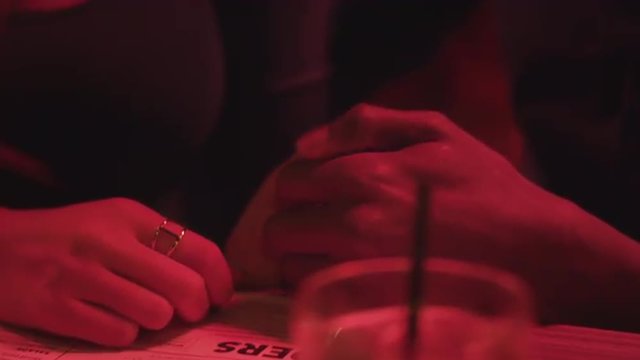 Closeup of a couple having a thumb war at a bar