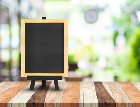 Blackboard menu with easel on wooden table with blur coffee shop