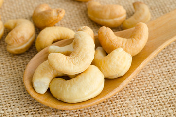 Cashews close-up in wooden spoon.