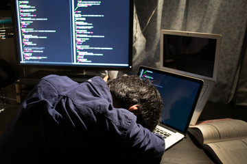 Exhausted Asian engineer sleeping on his laptop