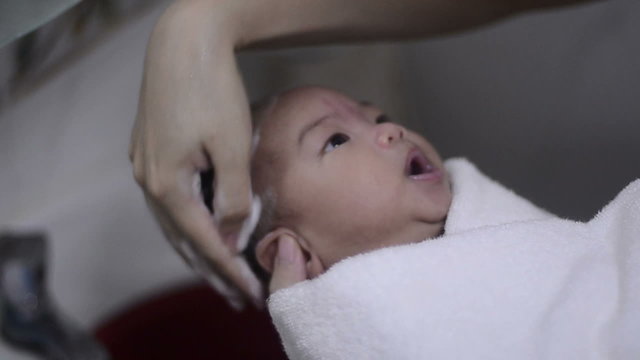 Mother is carefully washing her infant hair