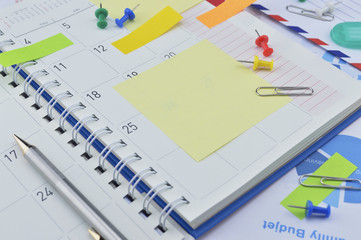 Pen with post It notes and pin on business diary page