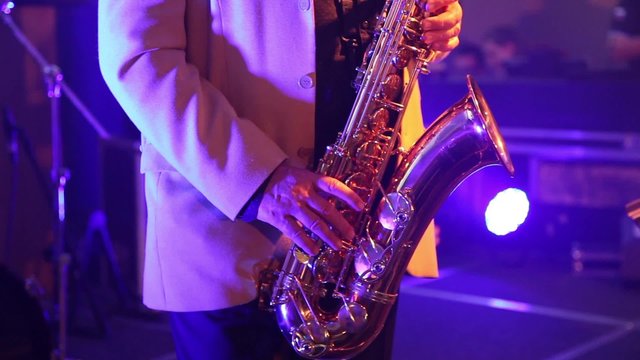 the man in the white suit playing the saxophone at the party